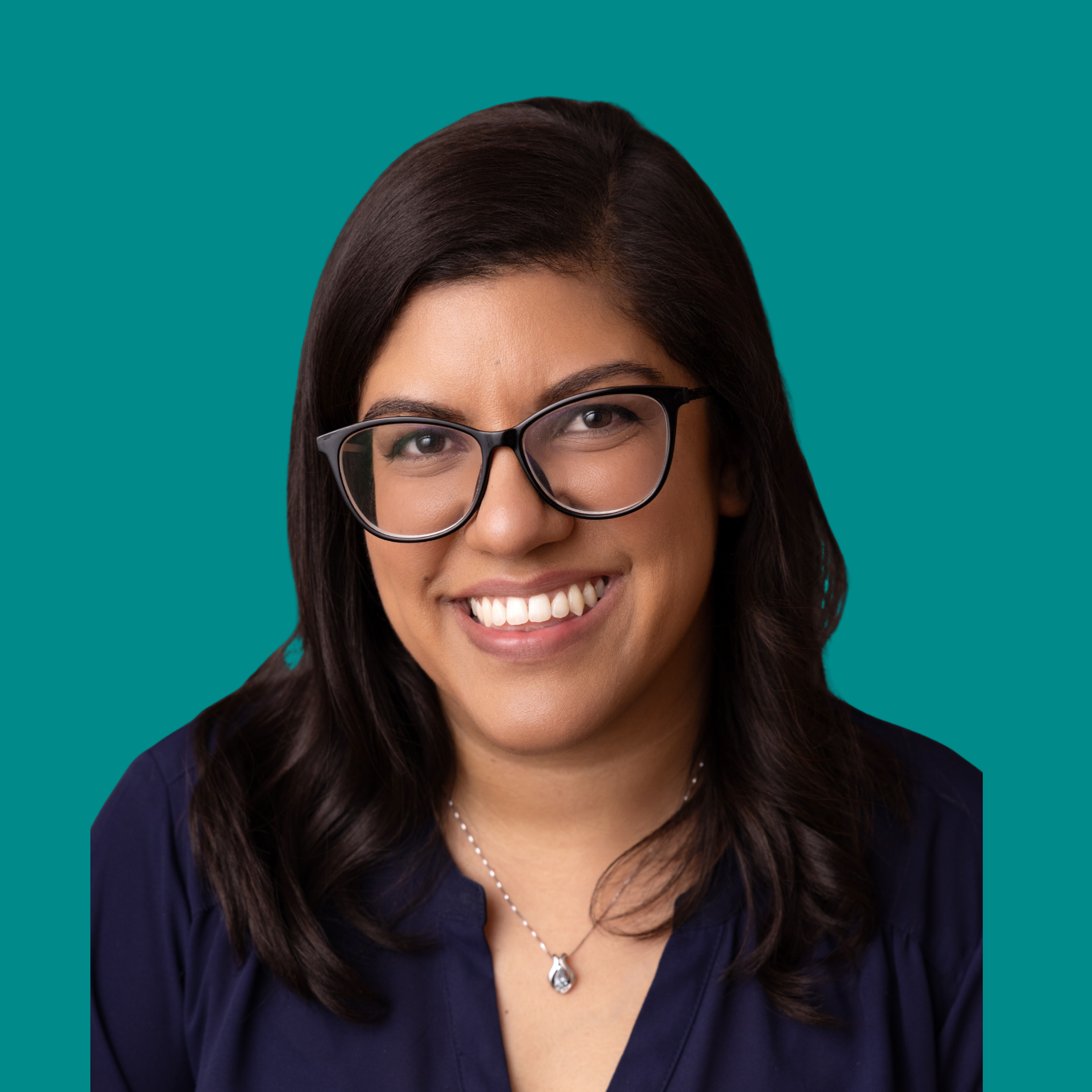 Headshot of Alana Sookoor, social worker and psychotherapist, smiling against a teal background, wearing glasses and a navy blouse.