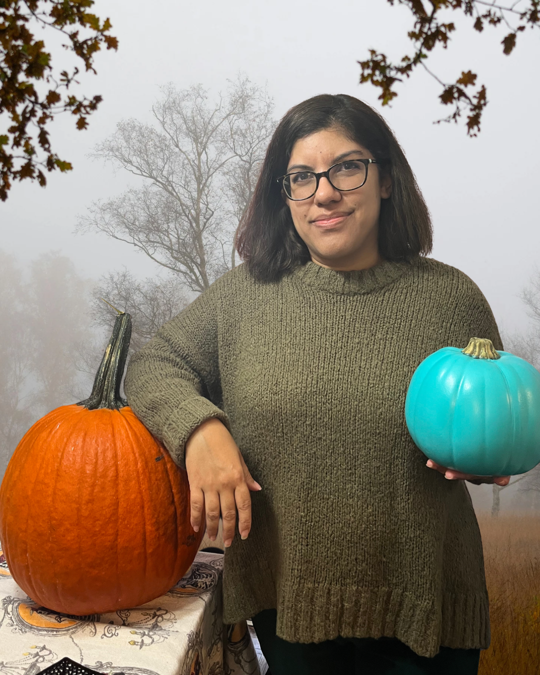 Alana Sookoor, Registered Social Worker and Psychotherapist at Elite Counselling, poses with orange and teal pumpkins against a misty autumn backdrop for a blog about Halloween activities, parenting, and connecting with children through play.